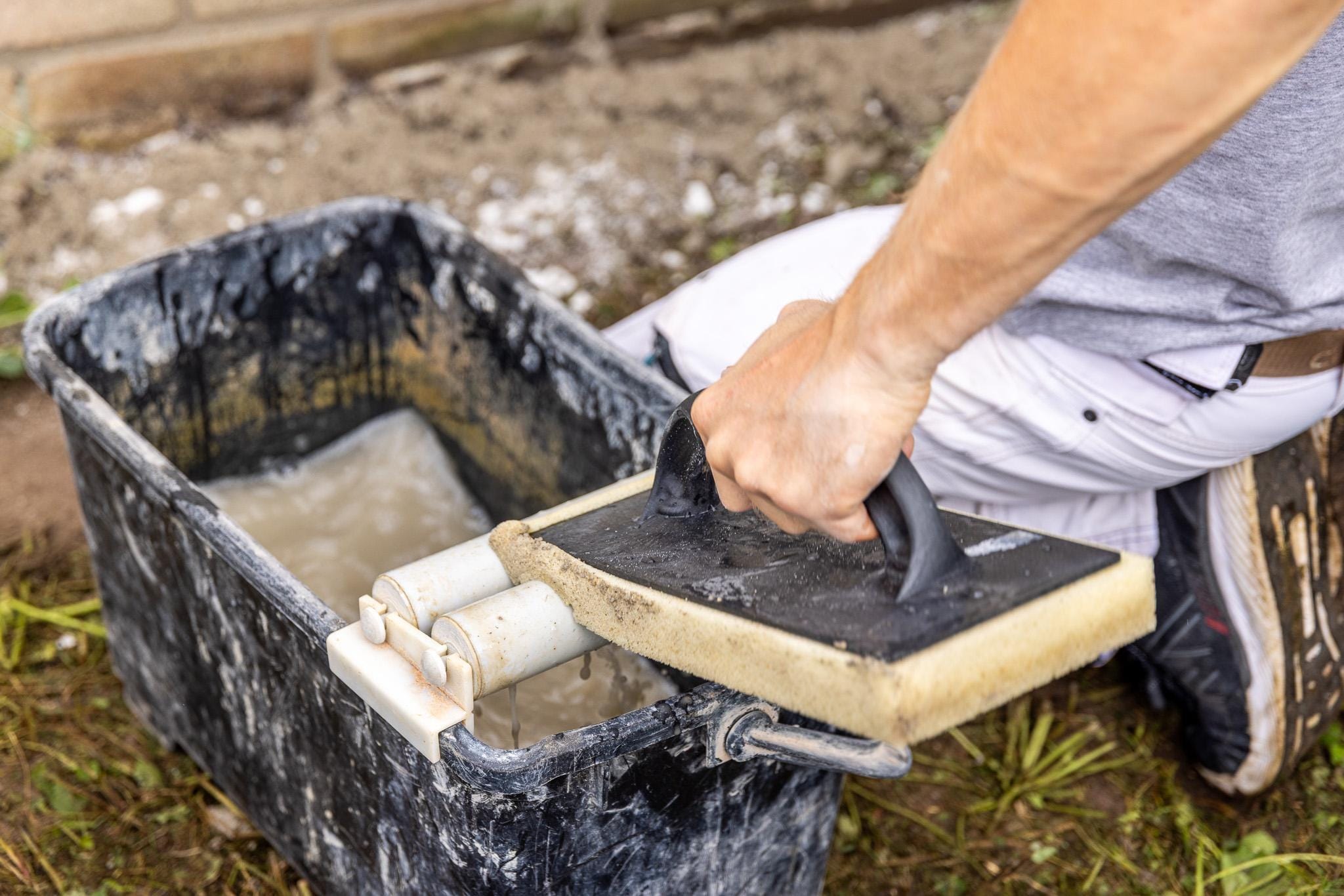 Hånd vasker flisesvamp i spand med vand