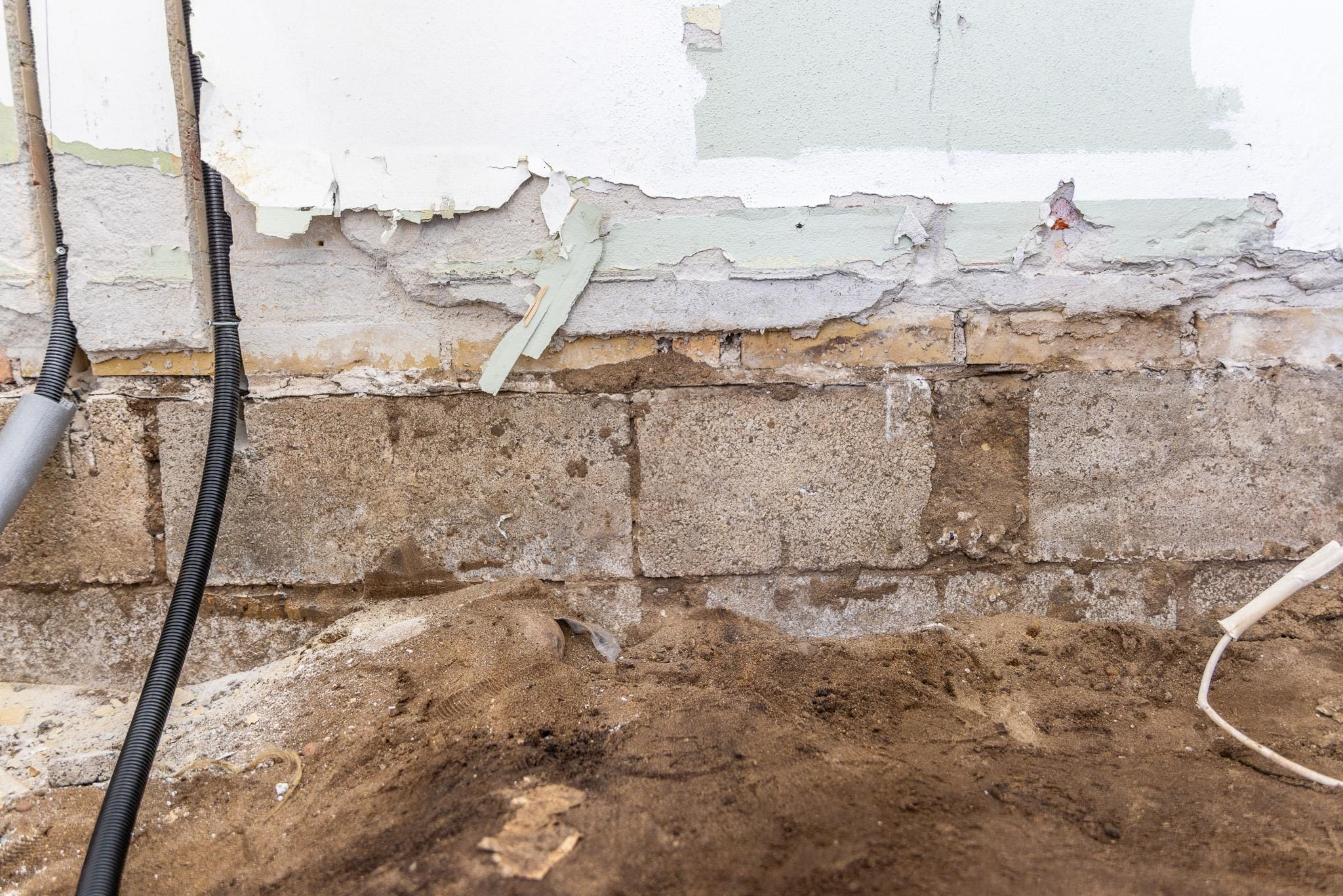 Fugtig kældervæg med skadet puds og rør