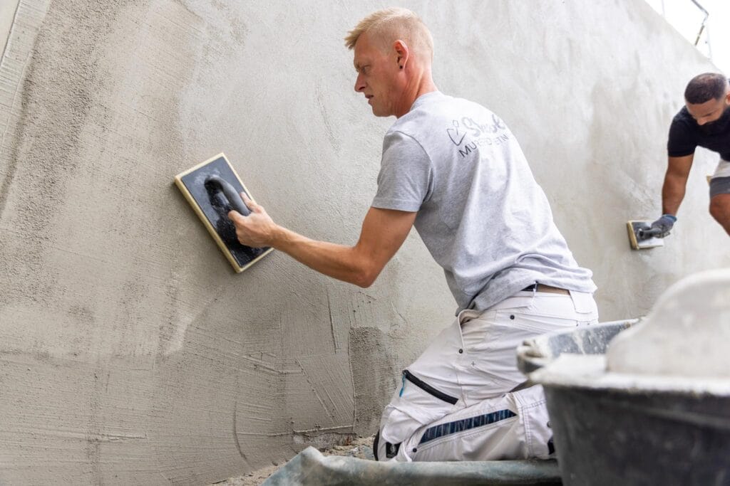 Håndværkere pudser væg med cement